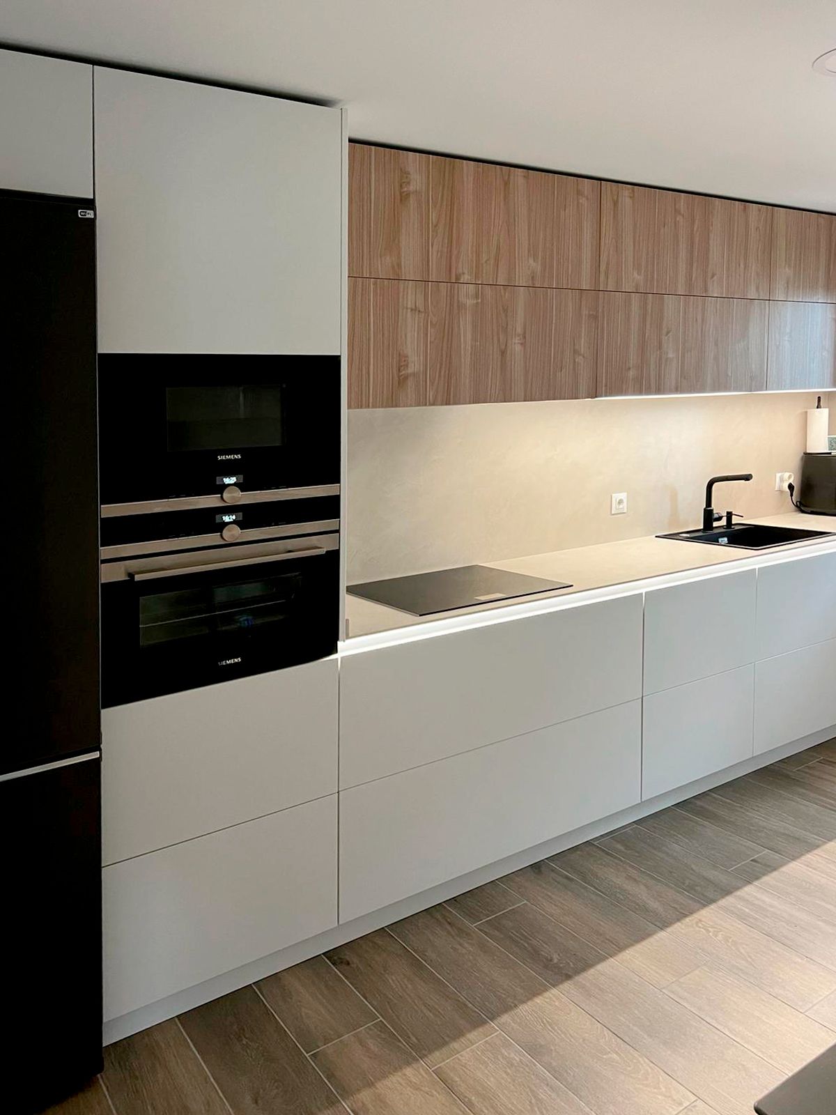 Cocina moderna en blanco y madera con encimera clara y grifería negra diseñada por Soinco
