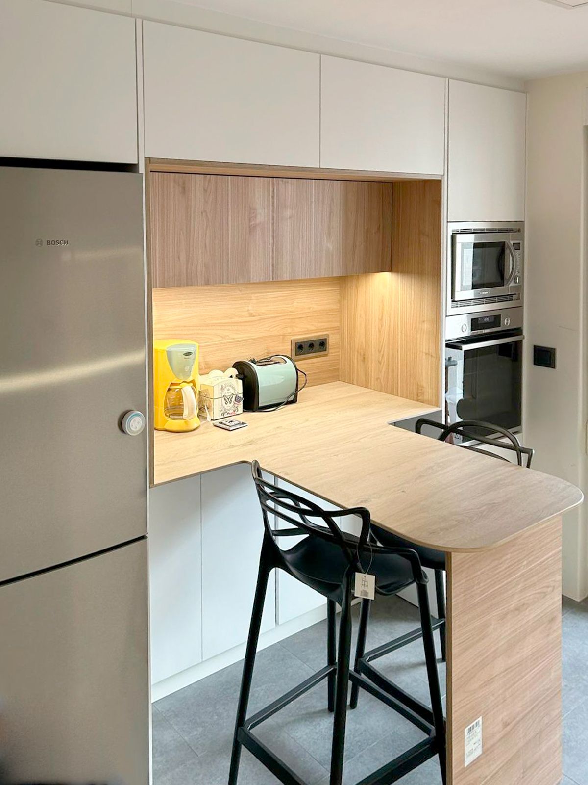 Cocina blanca y madera con barra funcional diseñada por Soinco