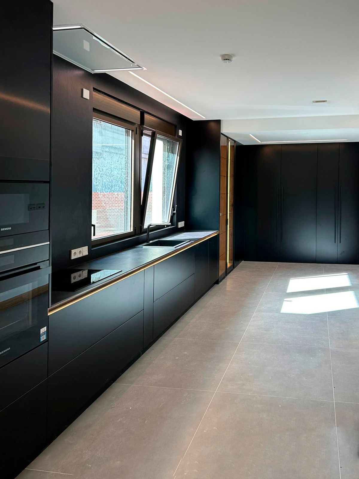 Cocina negra contemporánea con iluminación integrada y armarios a medida Soinco