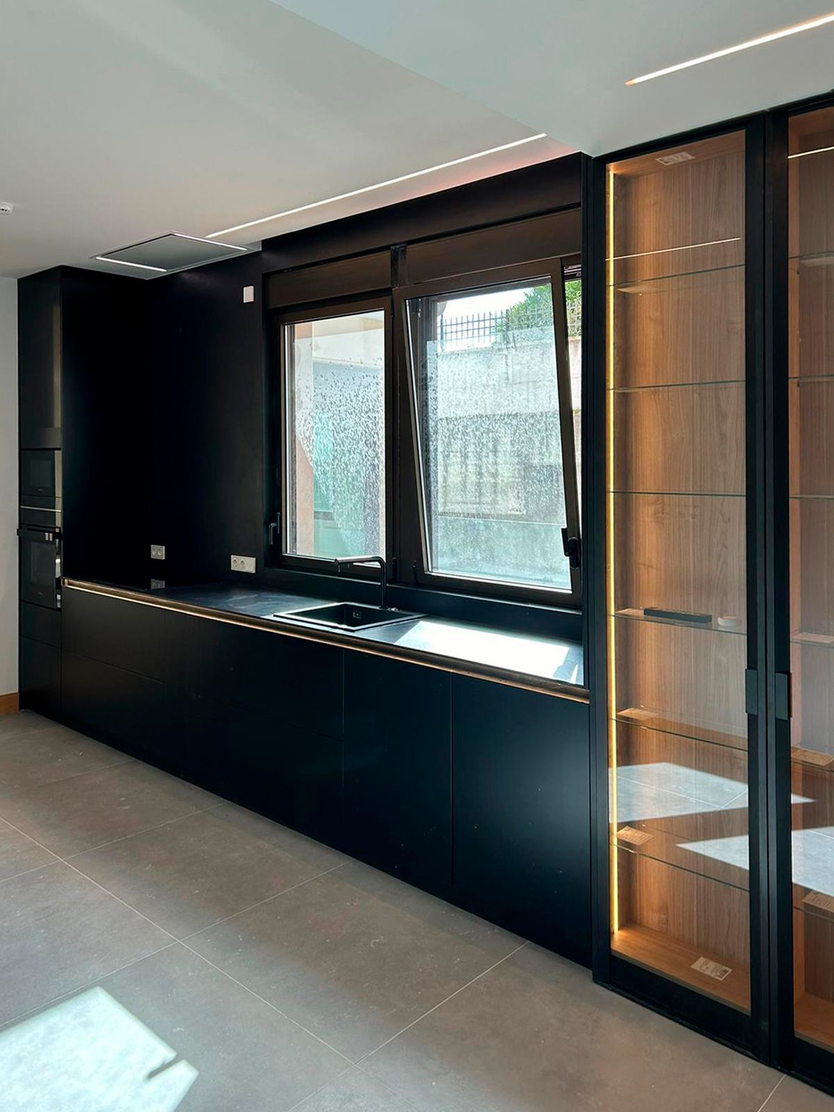 Cocina negra contemporánea con iluminación integrada y armarios a medida Soinco