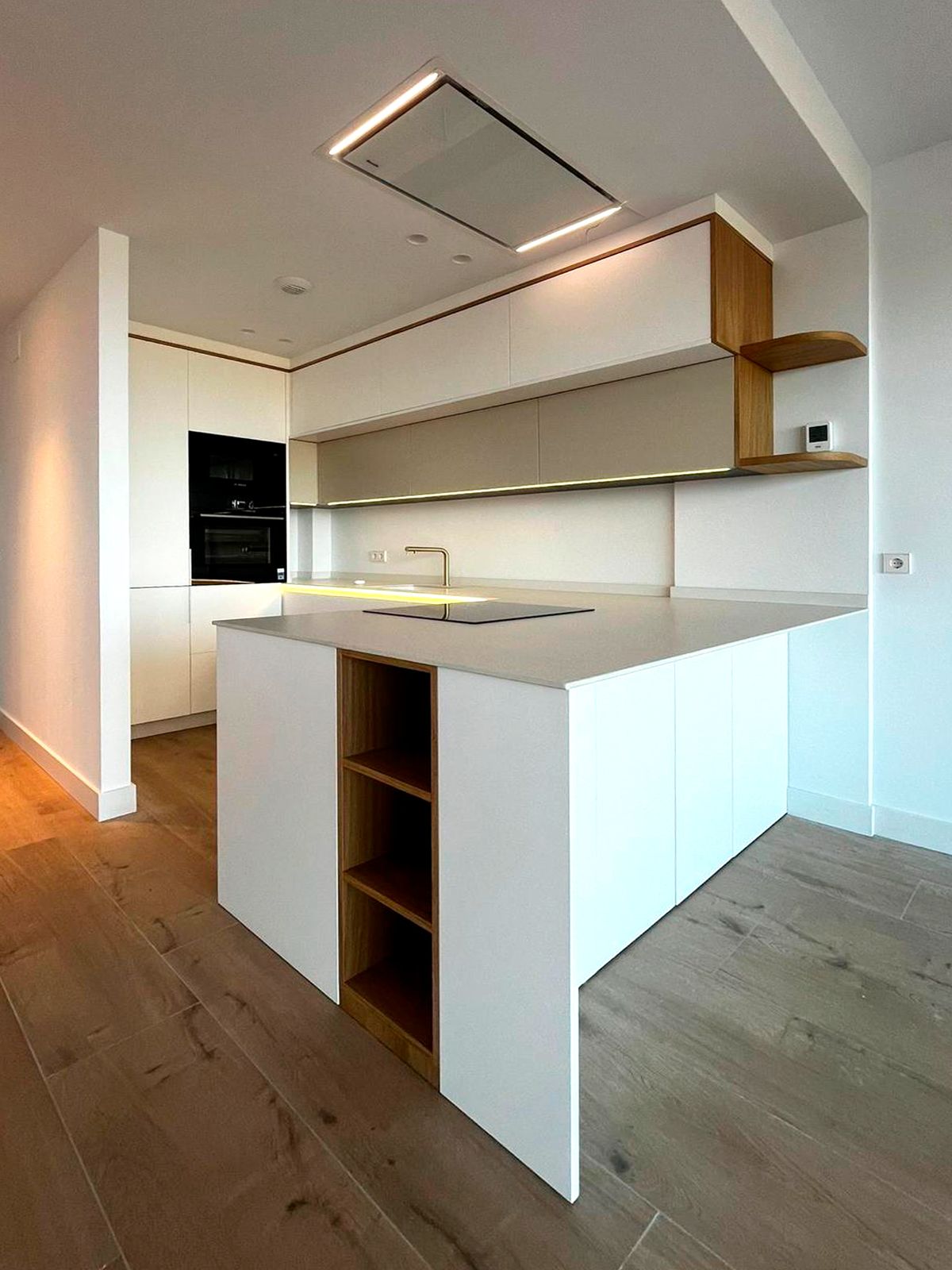 Cocina blanca con isla y estantería en madera natural