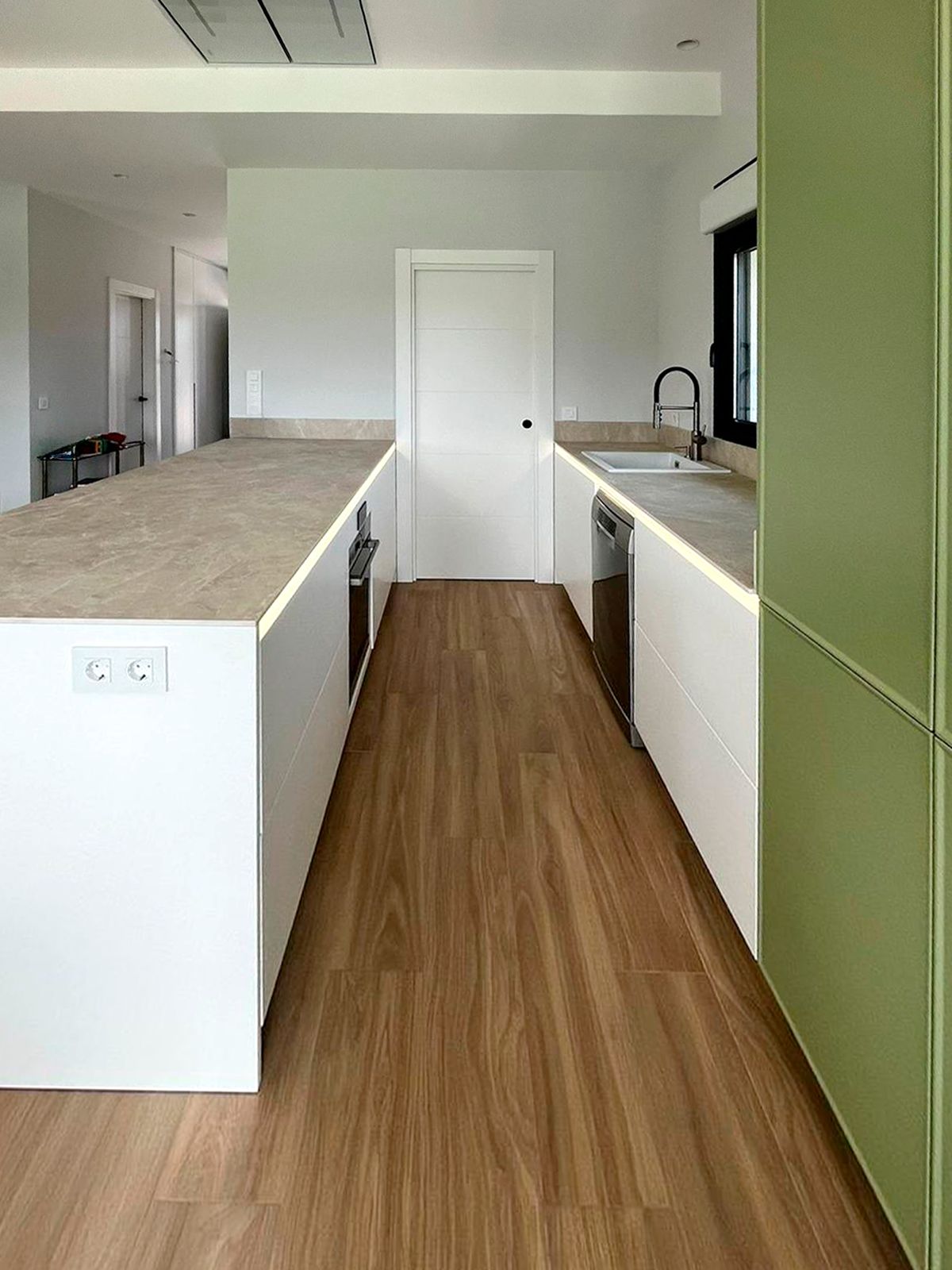 Cocina verde integrada al salón con diseño natural