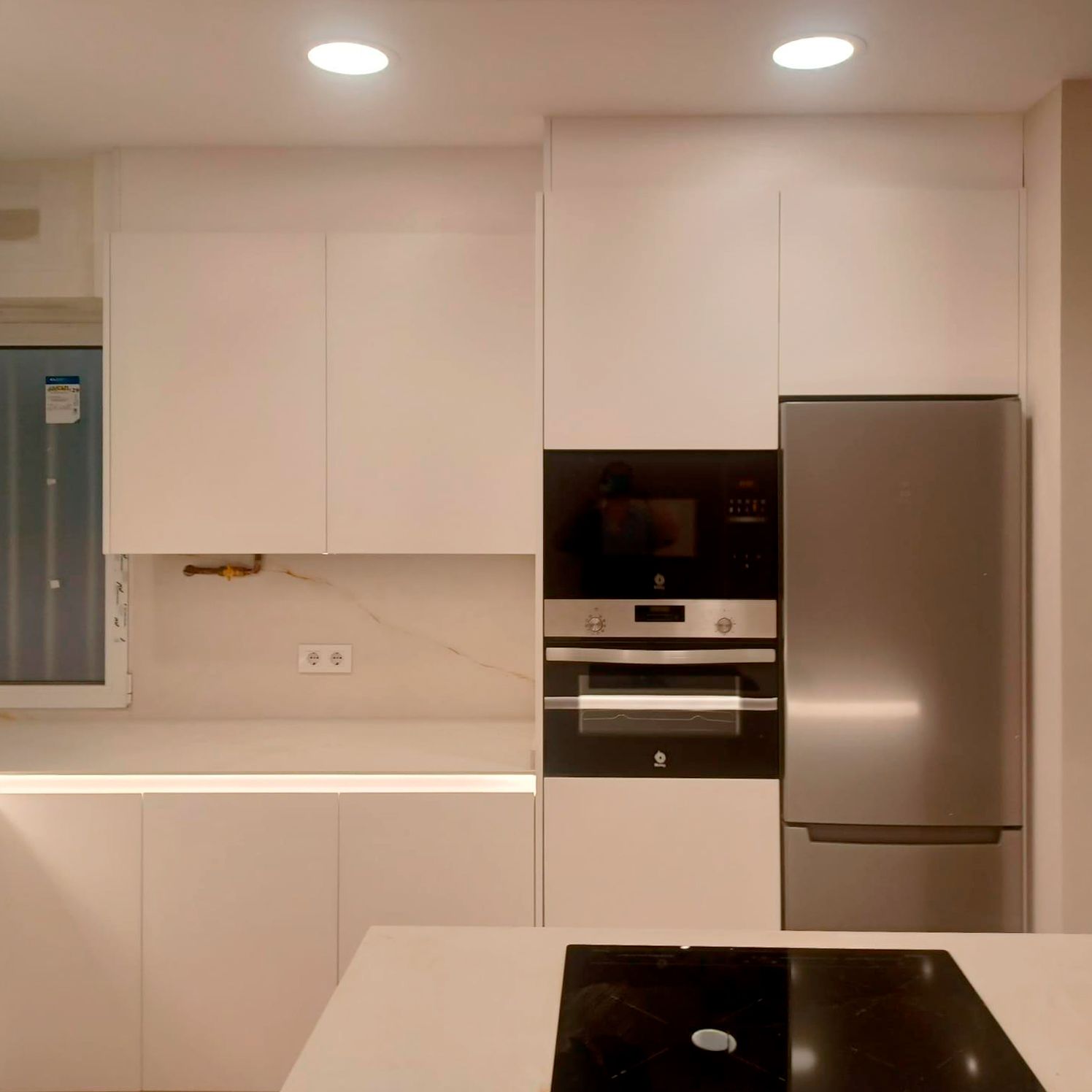 Cocina blanca moderna con fondo en madera y grifería negra Soinco