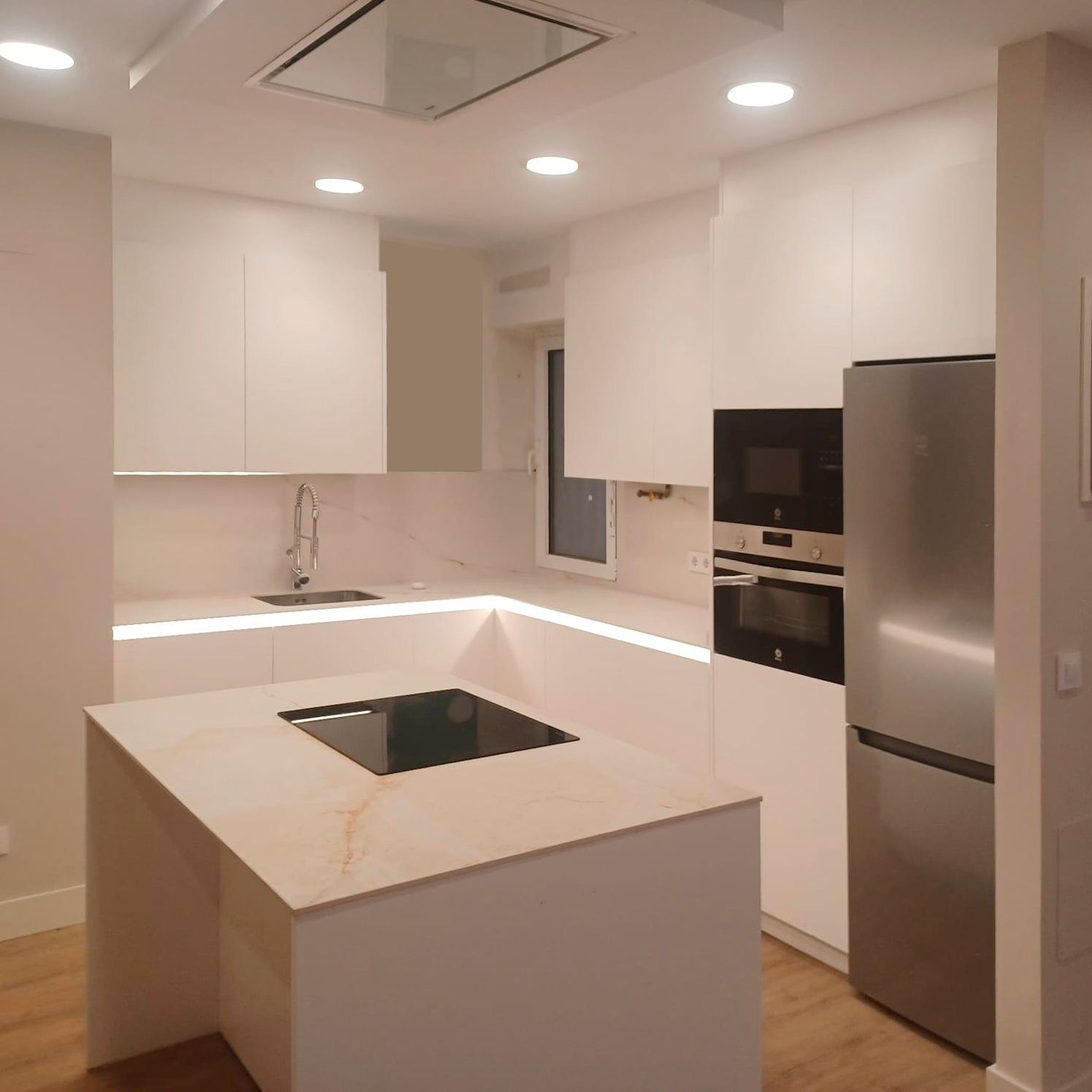 Cocina blanca moderna con isla central, madera y detalles en negro Soinco