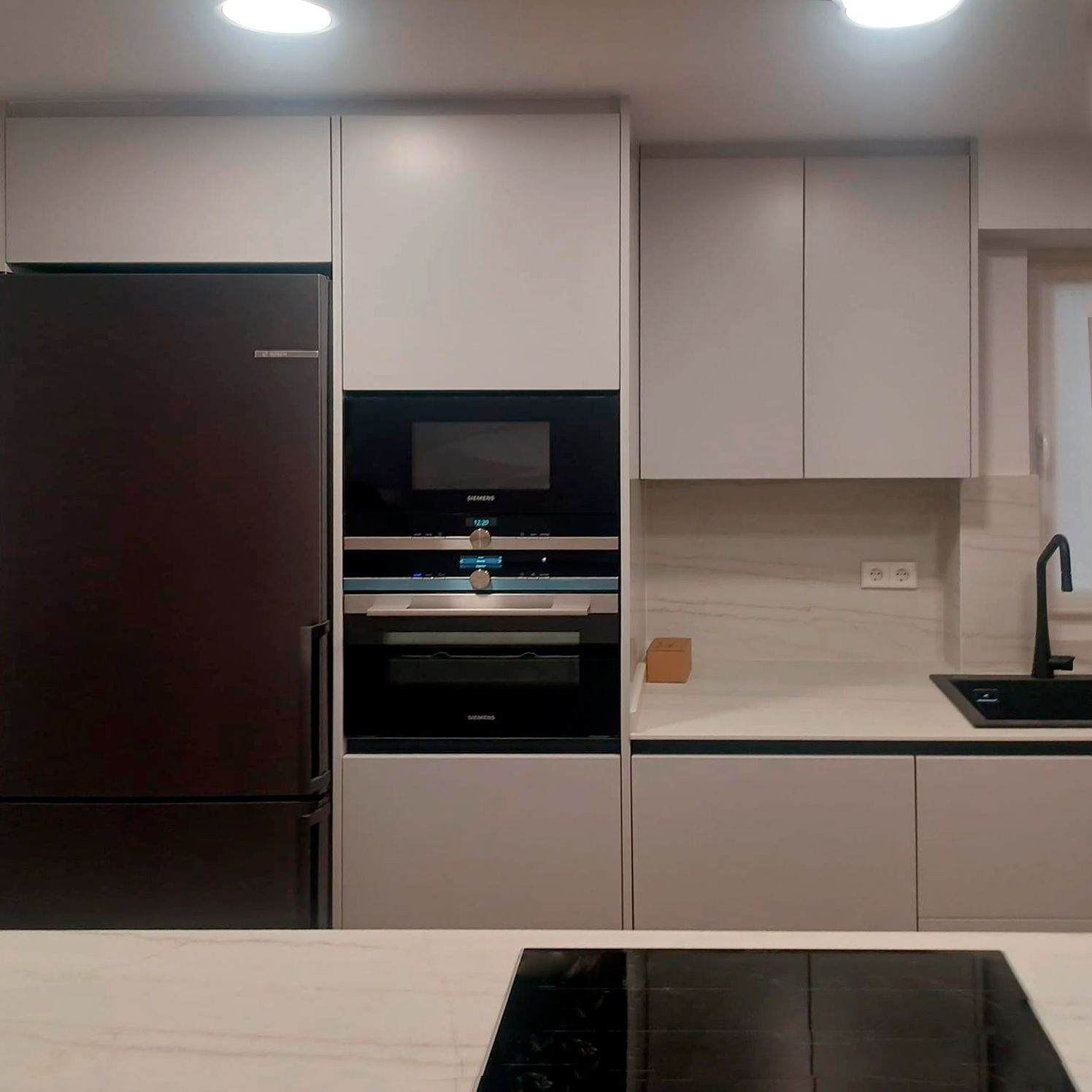 Cocina blanca moderna con fondo en madera y grifería negra Soinco