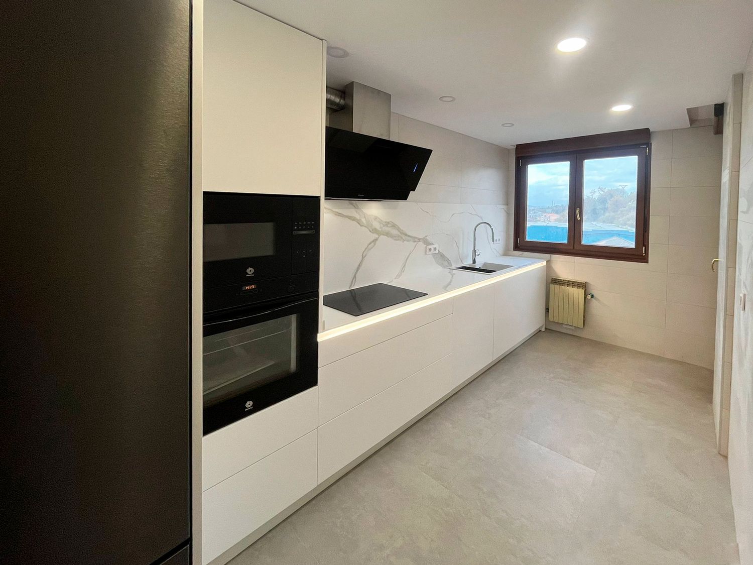 Cocina blanca con encimera efecto mármol y campana negra