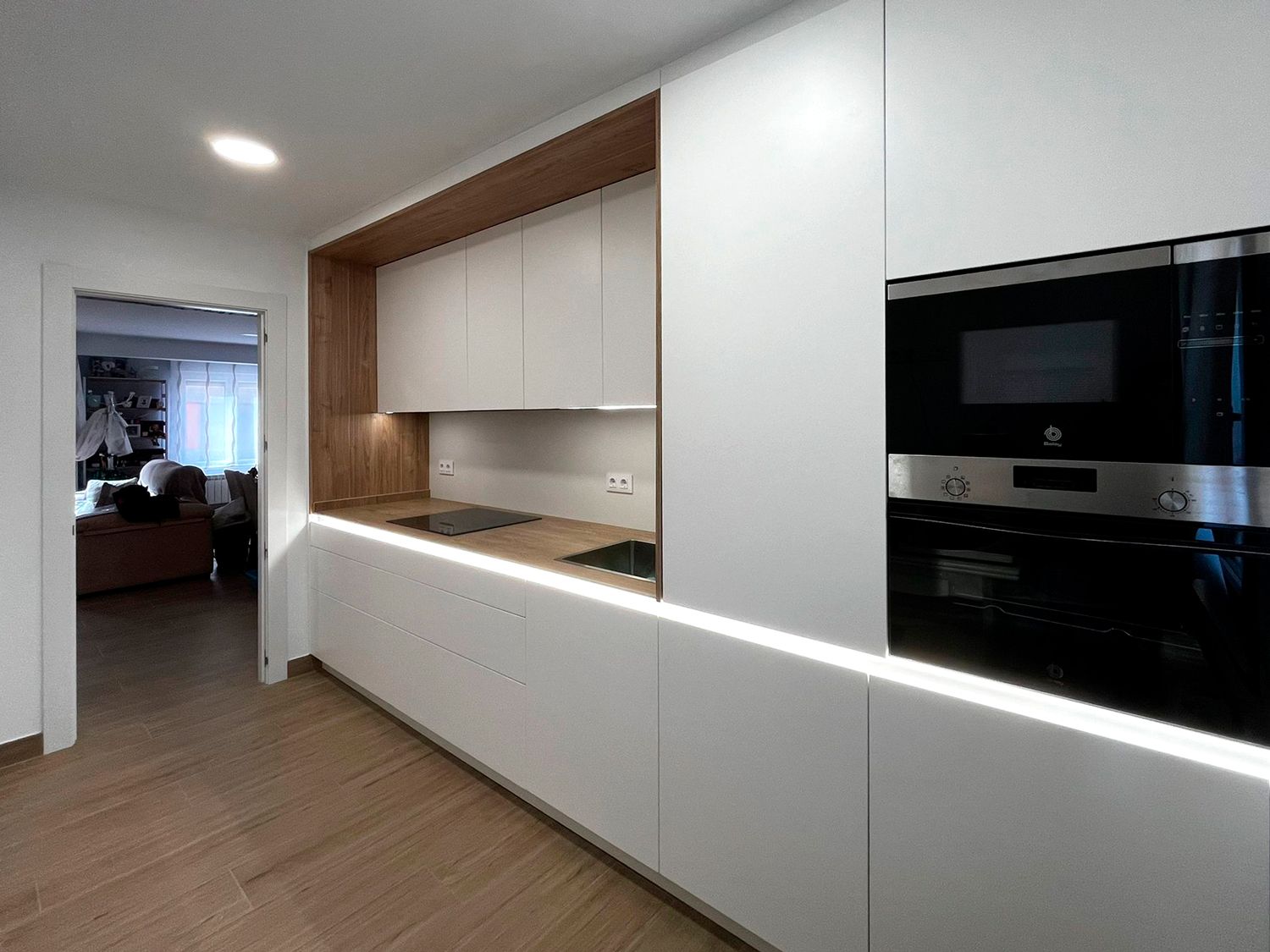 Cocina blanca con madera natural y electrodomésticos integrados