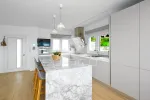 Cocina con isla de marmol y mobiliario blanco minimalista