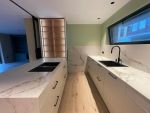 Cocina con península porcelánica y mobiliario en madera natural y beige diseñada por Cocinas Soinco.