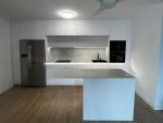Cocina blanca sin tiradores abierta al salón con isla y encimera porcelánica efecto mármol iluminada con LED en Cantabria | Soinco