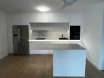 Cocina blanca sin tiradores abierta al salón con isla y encimera porcelánica efecto mármol iluminada con LED en Cantabria | Soinco