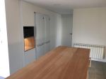 Muebles columna empotrados de suelo a techo con frigorífico integrado y hornacina de madera iluminada.