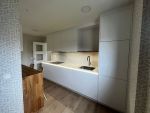 Cocina lineal estrecha blanca con muebles hasta el techo en Cantabria