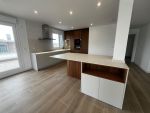 Cocina abierta con península, madera y tonos neutros diseñada a medida en Cantabria