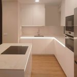 Cocina blanca moderna con isla central, madera y detalles en negro Soinco