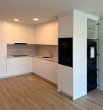 Cocina moderna con acabados naturales en madera clara y encimera beige.