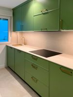 Cocina verde con tiradores dorados y encimera porcelánica clara Soinco