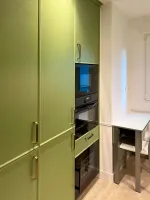 Cocina verde con tiradores dorados y encimera porcelánica clara Soinco