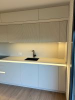 Detalle de muebles altos de cocina con textura acanalada en color Cloud Dancer Pantone.