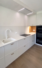 Encimera blanca con fregadero integrado y grandes cajoneras con tiradores metálicos.