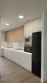 Cocina lineal blanca y madera diseñada a medida en Cantabria