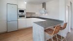 Cocina blanca y gris con encimera porcelánica y barra integrada Soinco