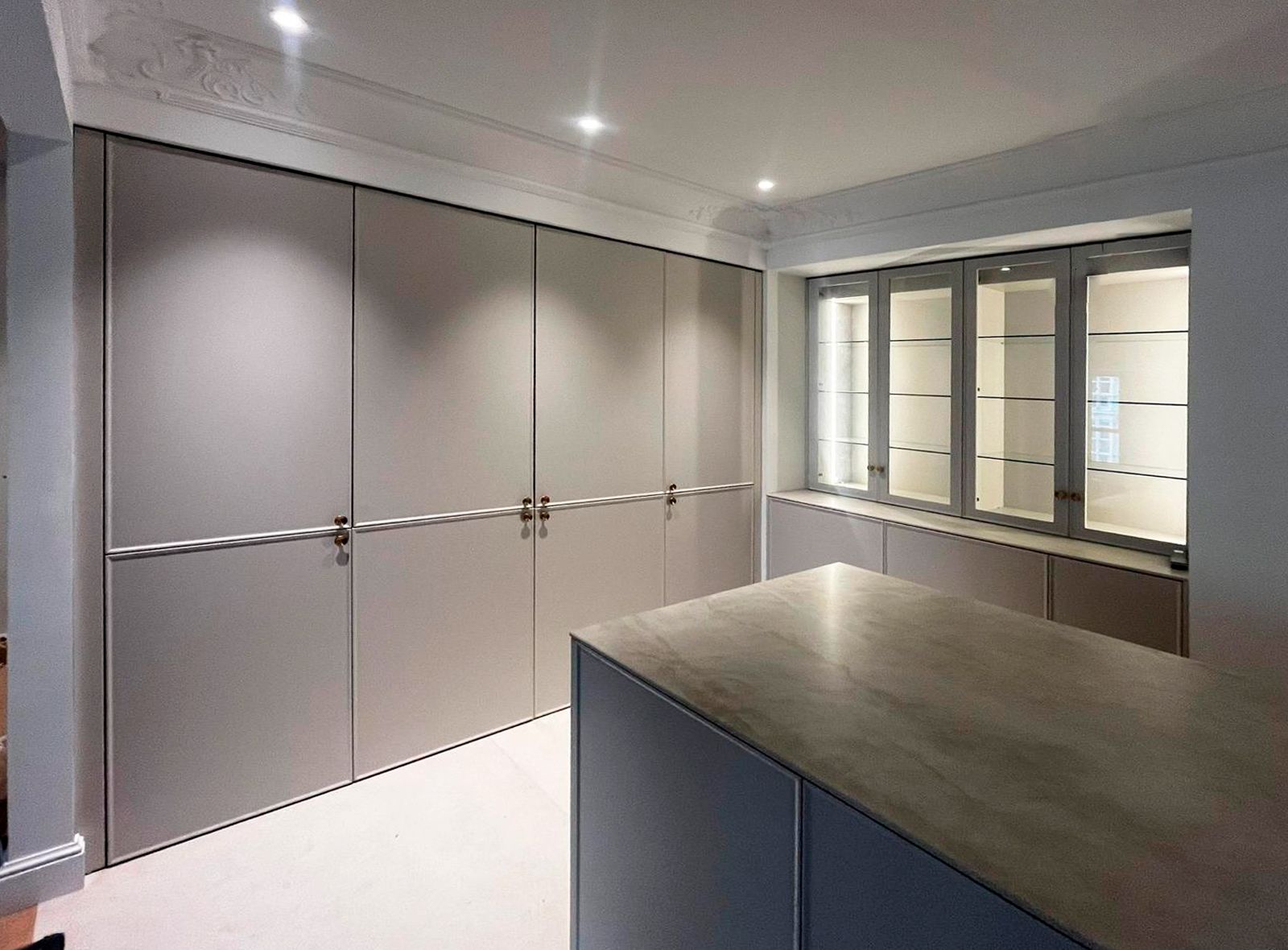 Armario oculto en cocina gris con interior en madera e iluminación LED