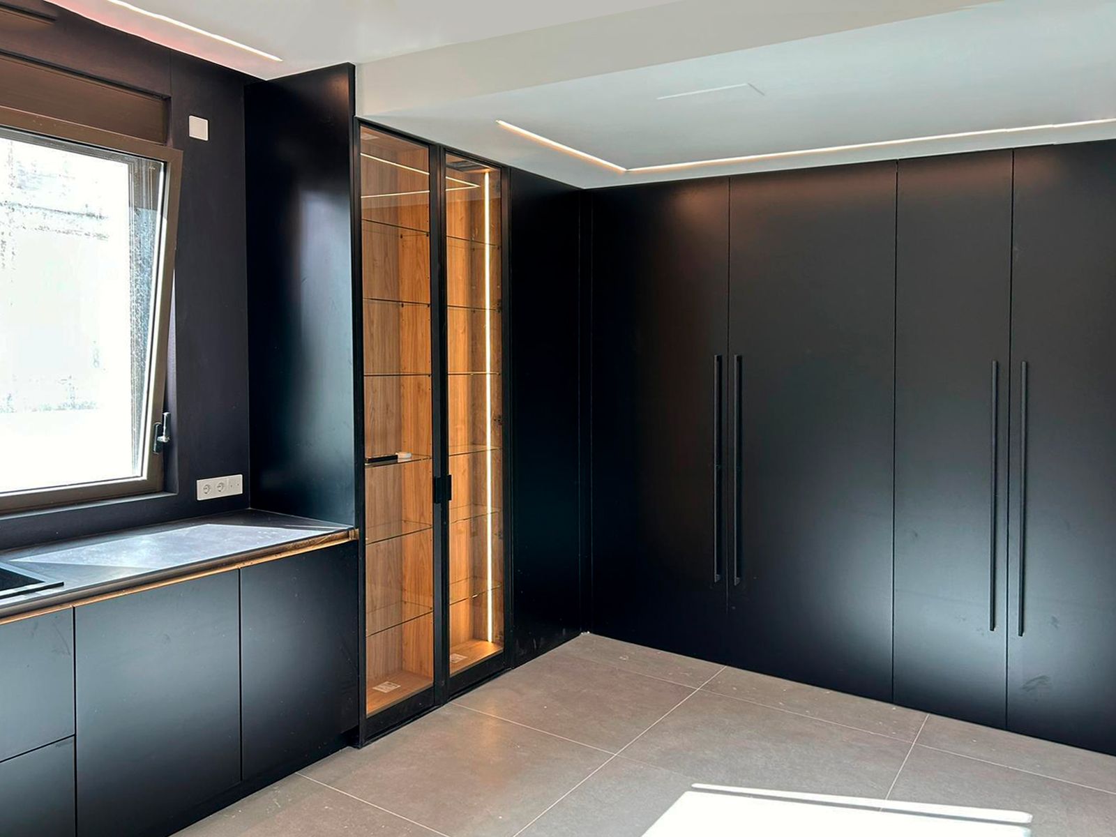 Cocina negra con frentes mate, vitrina iluminada y diseño contemporáneo.