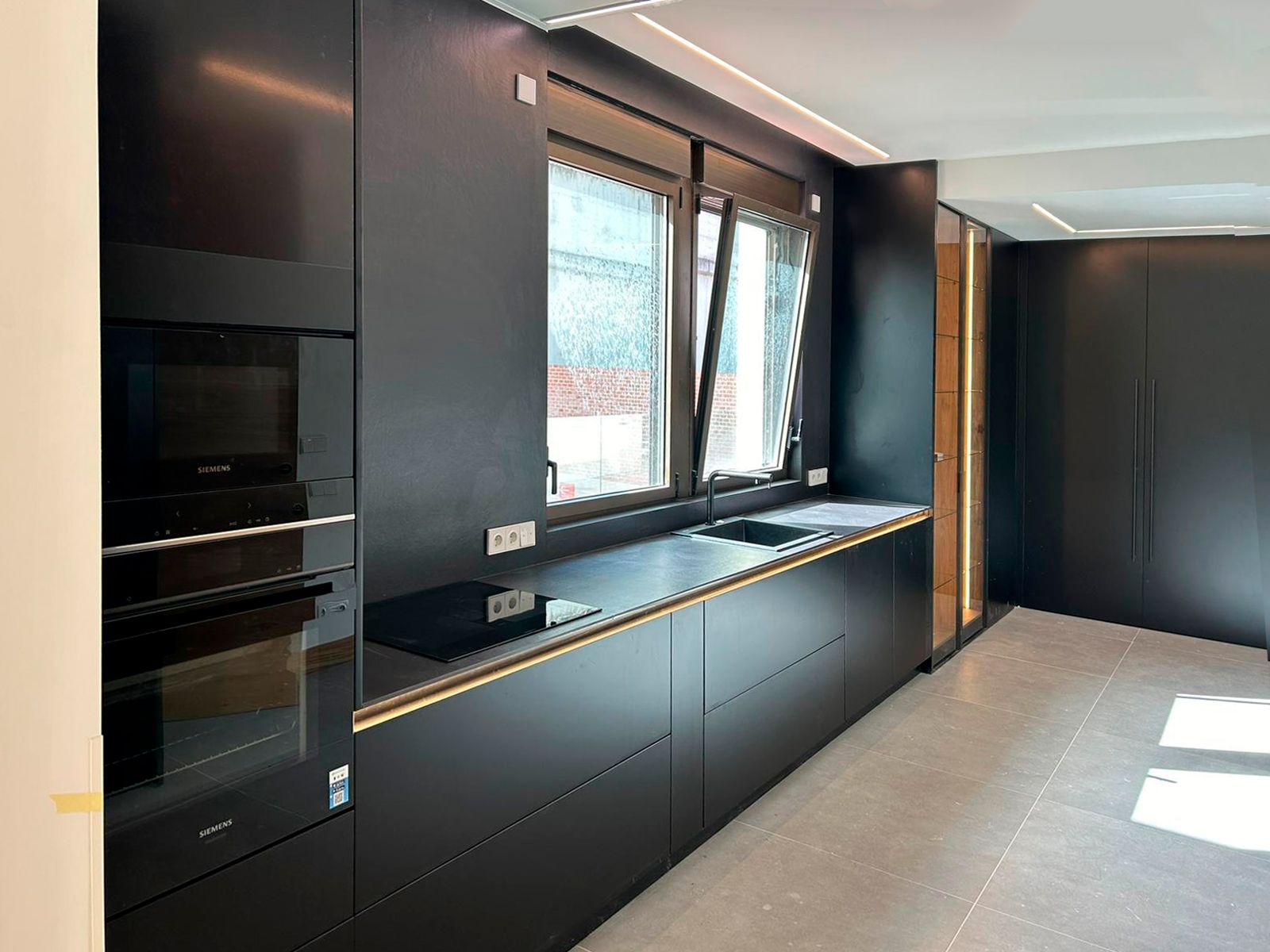 Cocina negra contemporánea con iluminación integrada y armarios a medida Soinco