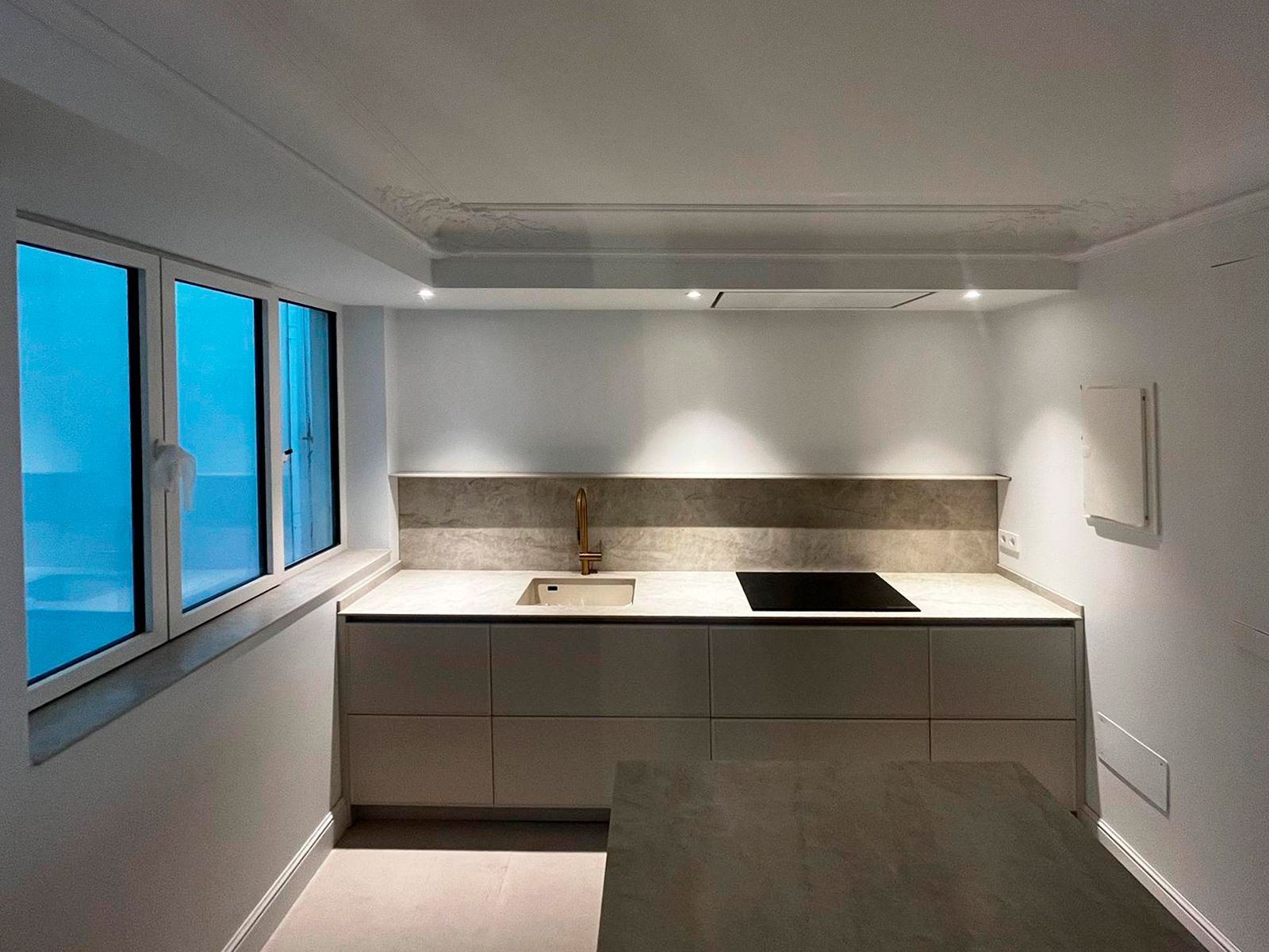 Cocina gris con encimera clara y grifo dorado