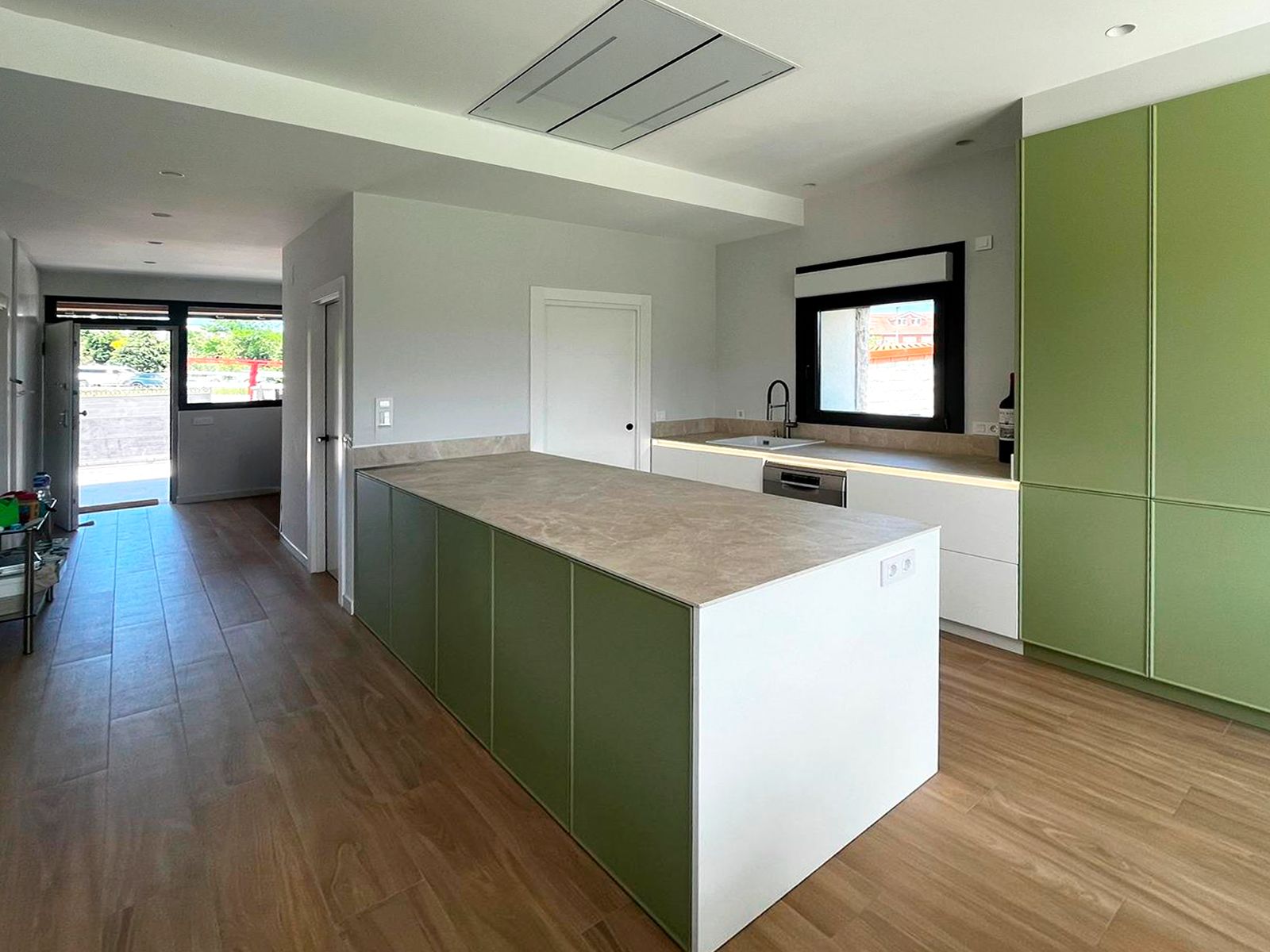 Cocina verde con isla central y encimera efecto piedra