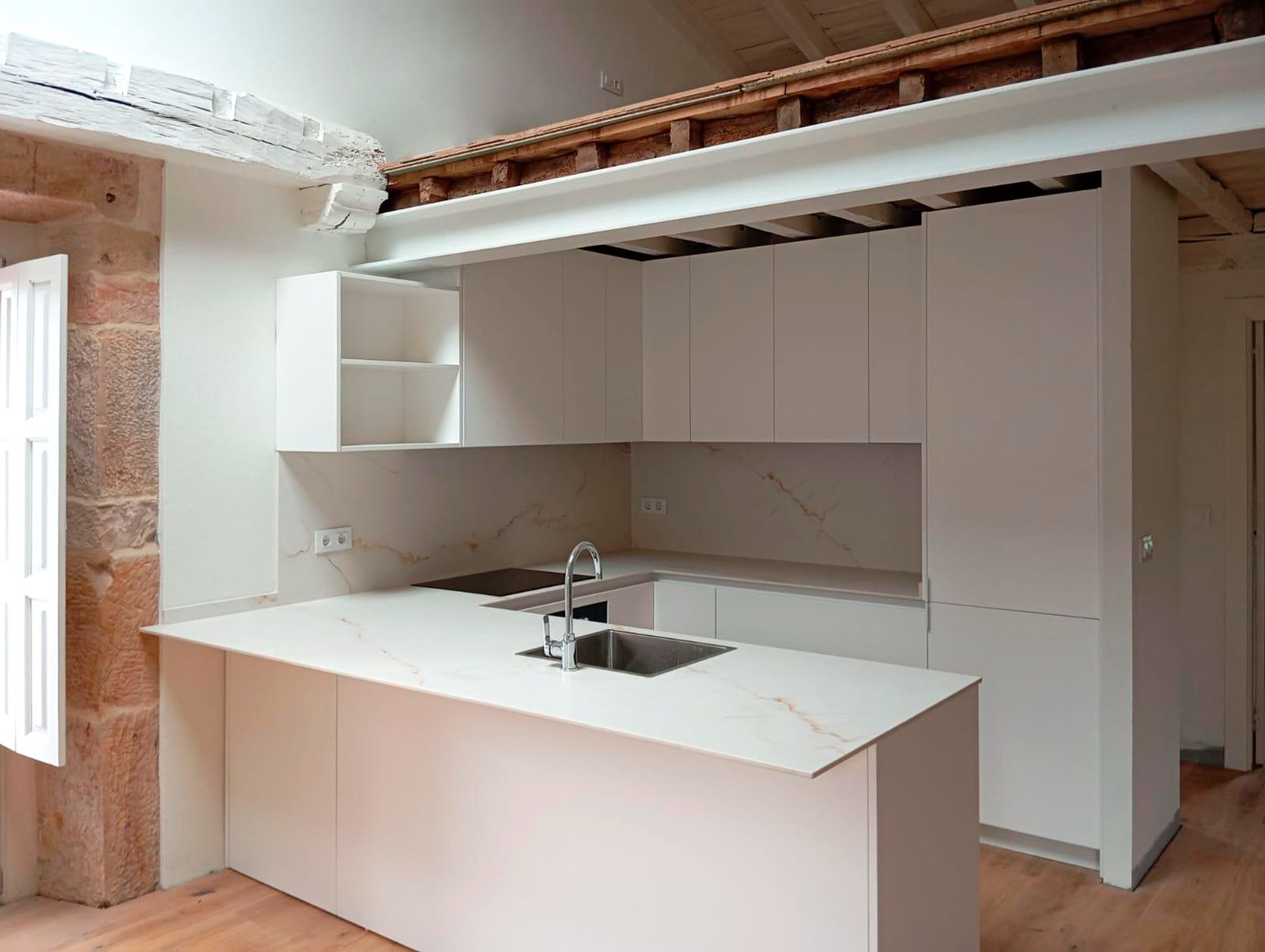 Cocina blanca moderna con encimera porcelánica y pared de piedra natural Soinco