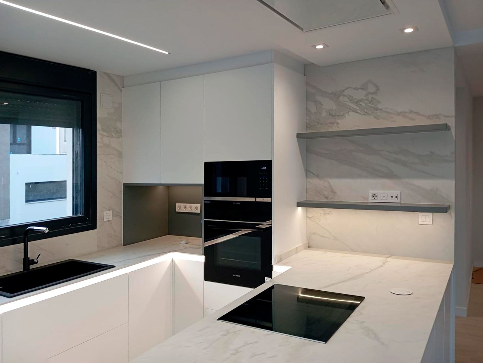 Detalle de cocina blanca con paredes y encimera efecto mármol
