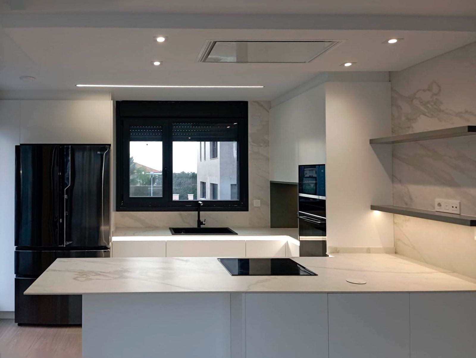 Cocina blanca con península y encimera efecto mármol