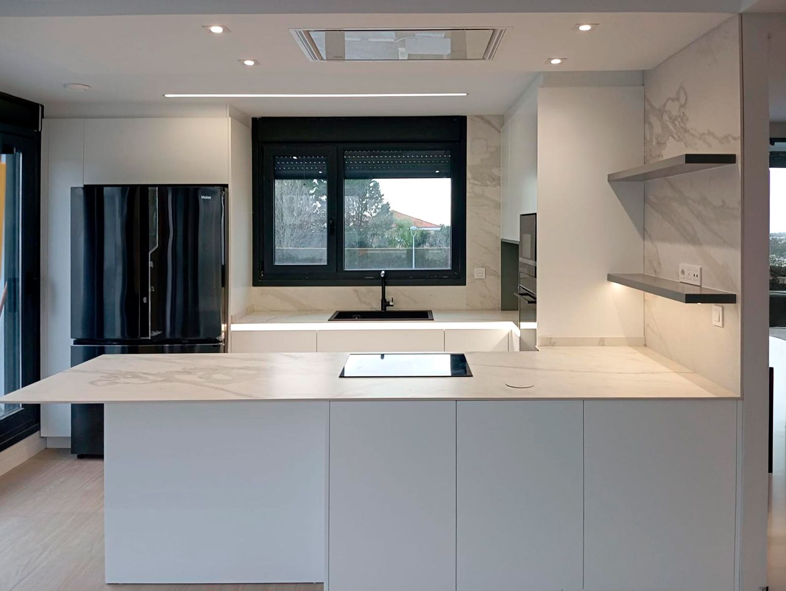 Cocina blanca con península y encimera efecto mármol