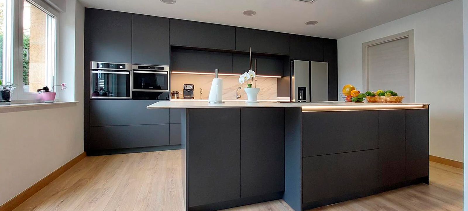 Cocina negra moderna con isla central y encimera efecto mármol diseñada por Soinco