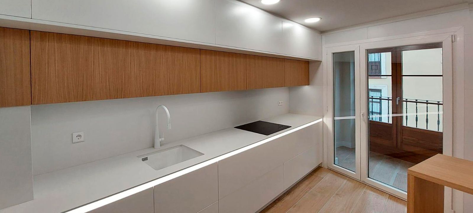 Cocina lineal blanca con muebles superiores en madera natural