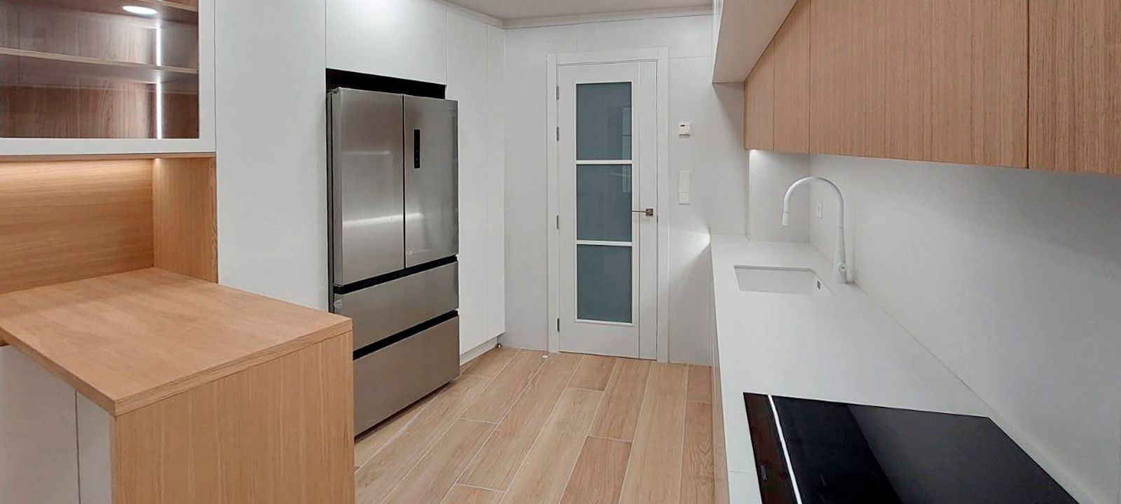 Cocina blanca y madera con encimera blanca y suelo en madera clara