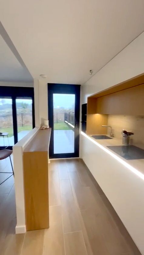 Cocina blanca abierta al salón con barra de madera